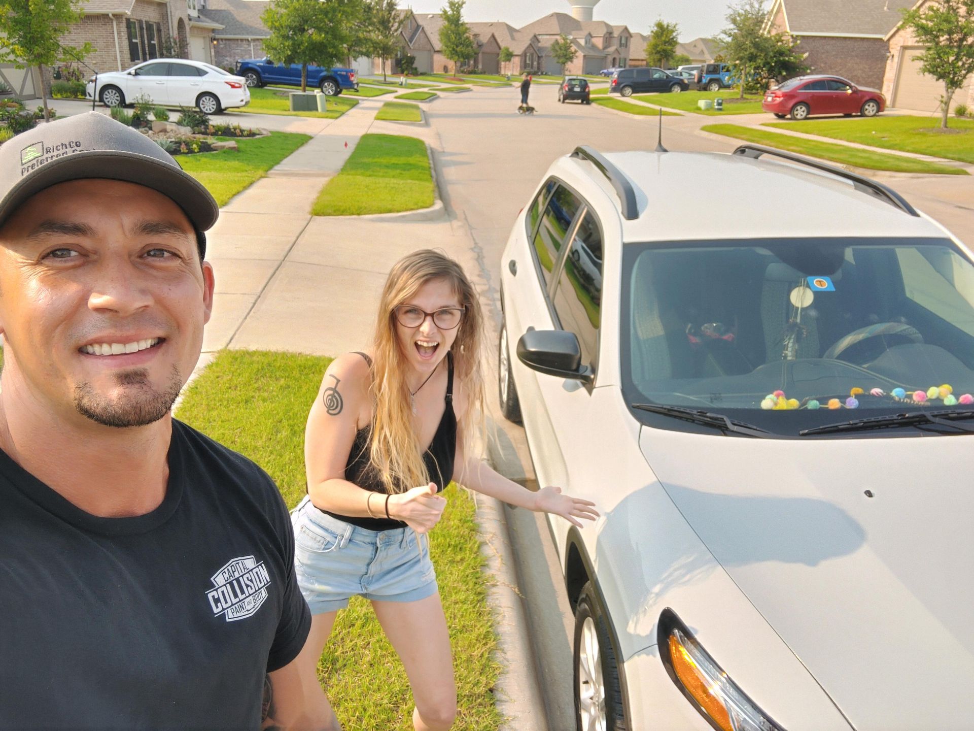A man and a woman are posing for a picture in front of a car.