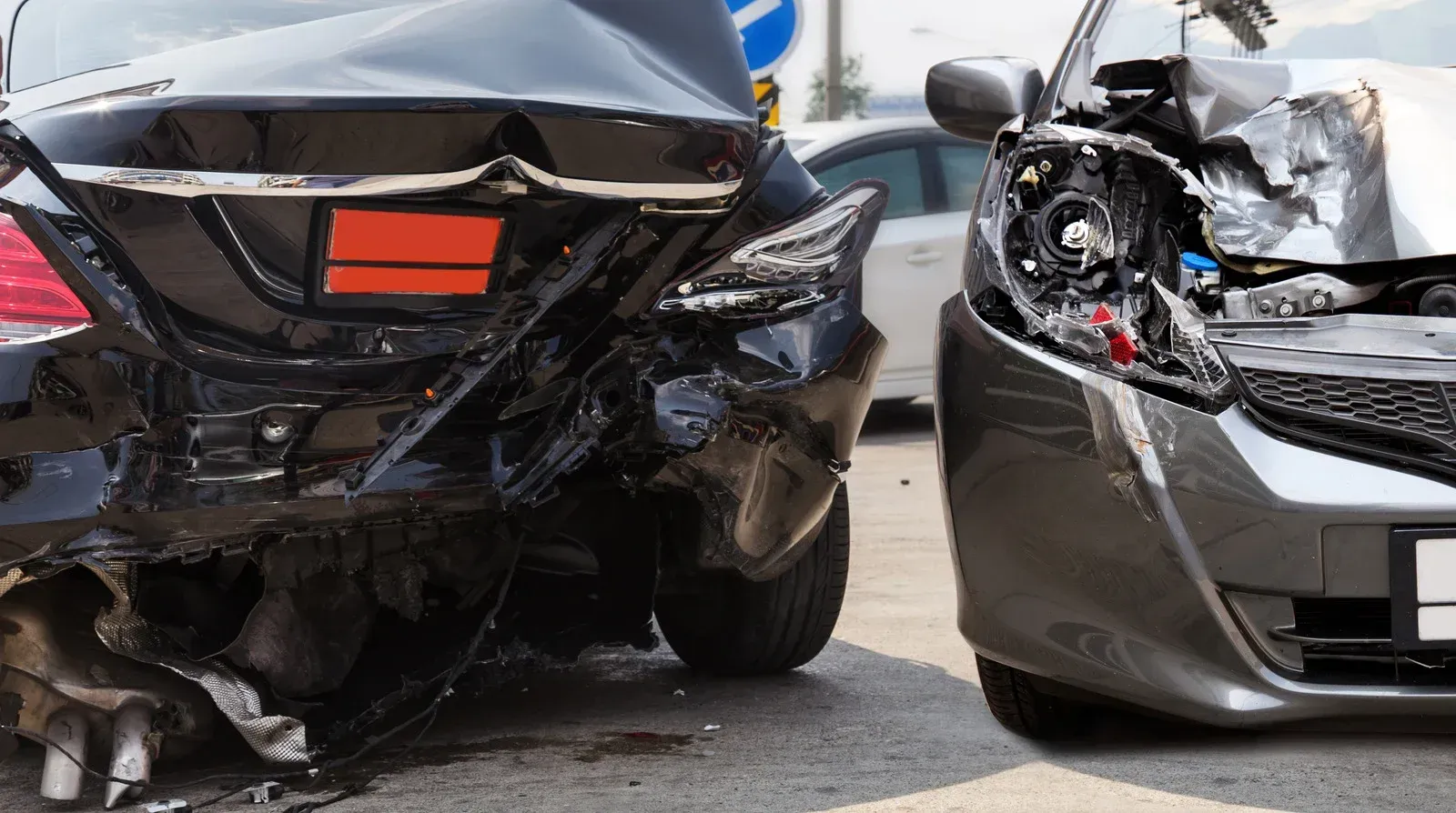 Two cars are damaged in a car accident on a city street.