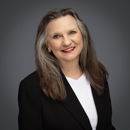A woman in a black jacket and white shirt is smiling for the camera.