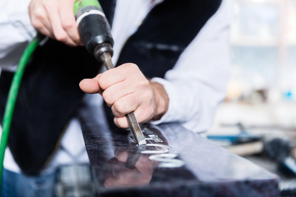 A Man Is Using a Drill to Carve a Name Into a Piece of Granite — Nick Locke Monuments in Macksville, NSW