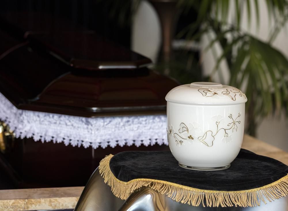 A White Urn Is Sitting on A Table in Front of A Coffin — Nick Locke Monuments in Bellingen, NSW