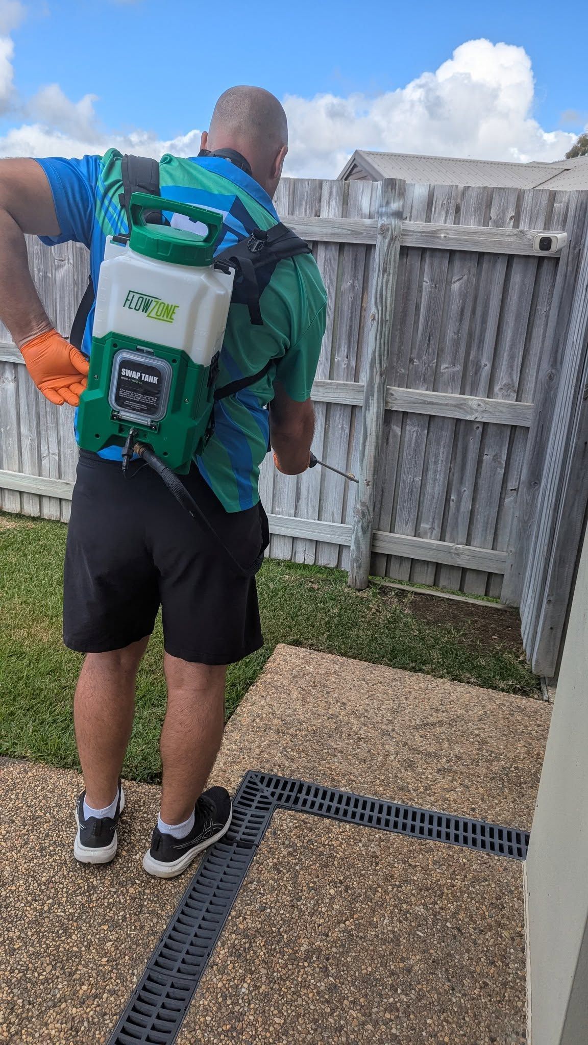 Person Spraying Insecticide Along a Wall Baseboard on Wooden Stairs — Total Pest and Carpet Cleaning in Yeppoon, QLD