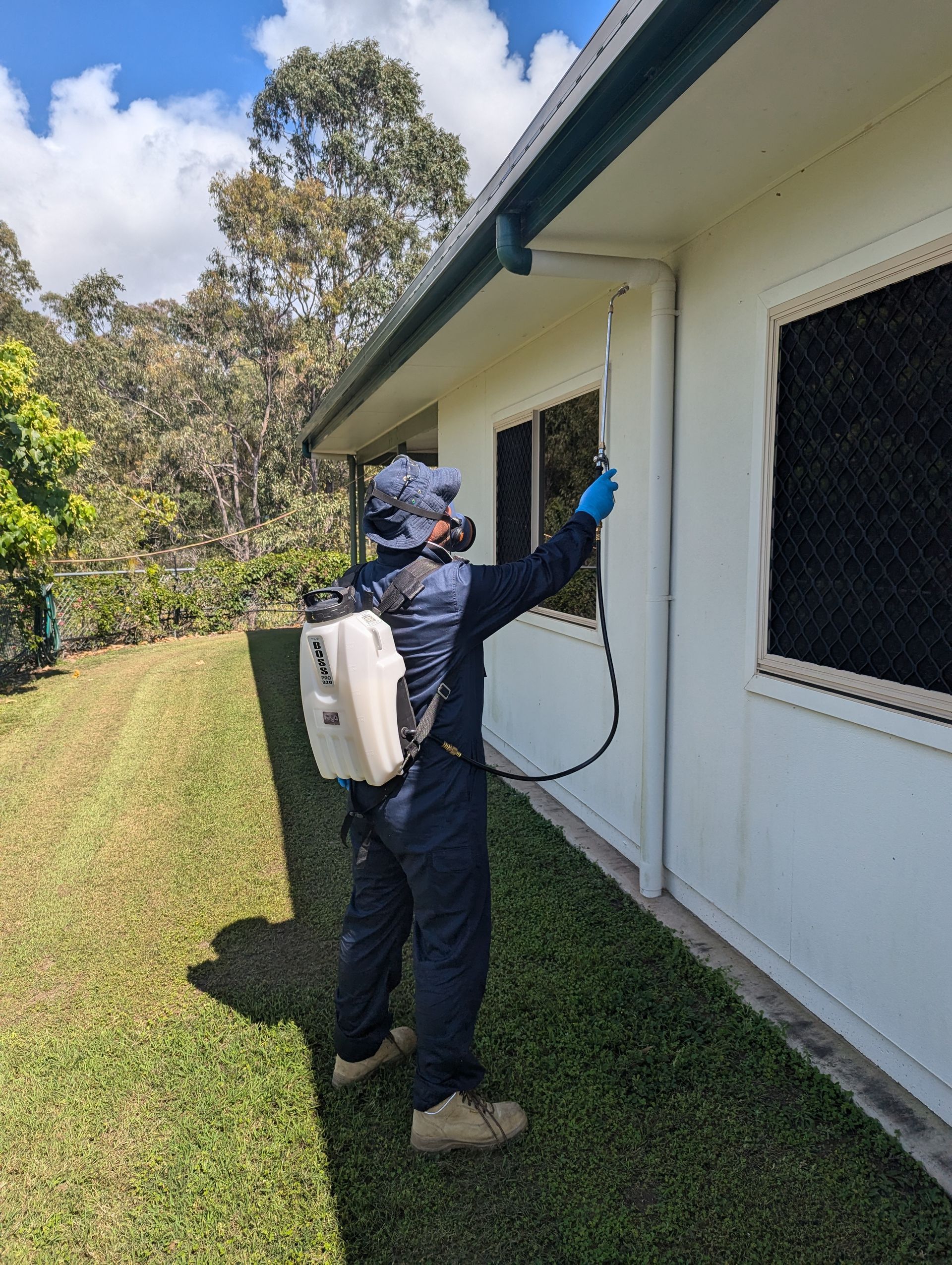 A Man Wearing a Gas Mask is Spraying a Room With a Sprayer — Total Pest and Carpet Cleaning in Kinka Beach, QLD