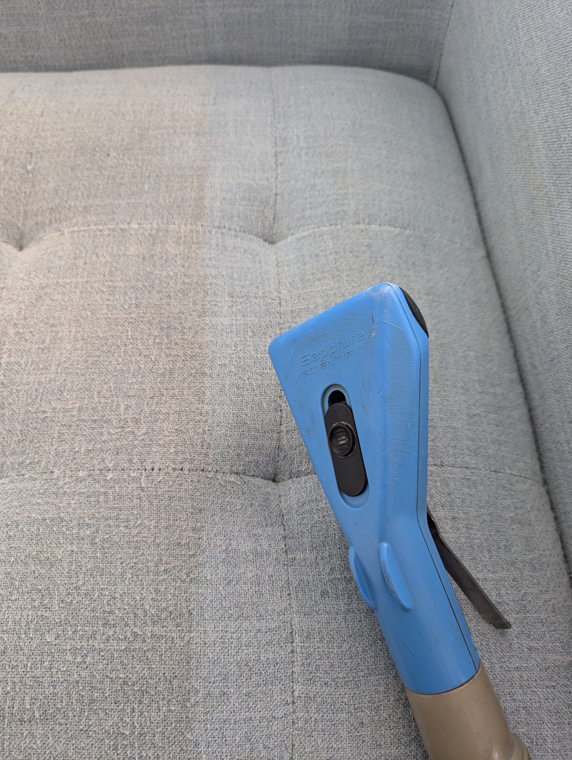 A Person is Spraying a Couch With a Sprayer in a Living Room — Total Pest and Carpet Cleaning in Kinka Beach, QLD