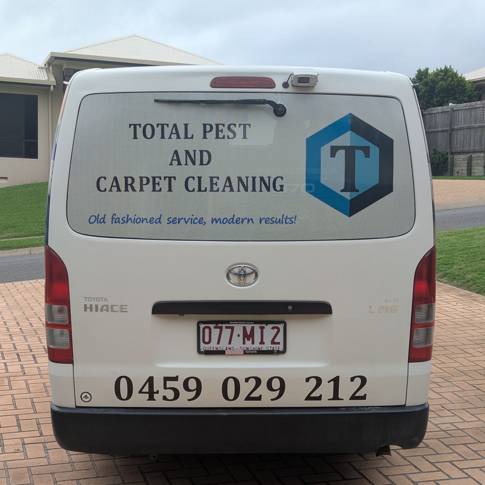 A Man is Spraying a Wooden Fence With a Sprayer — Total Pest and Carpet Cleaning in Yeppoon, QLD