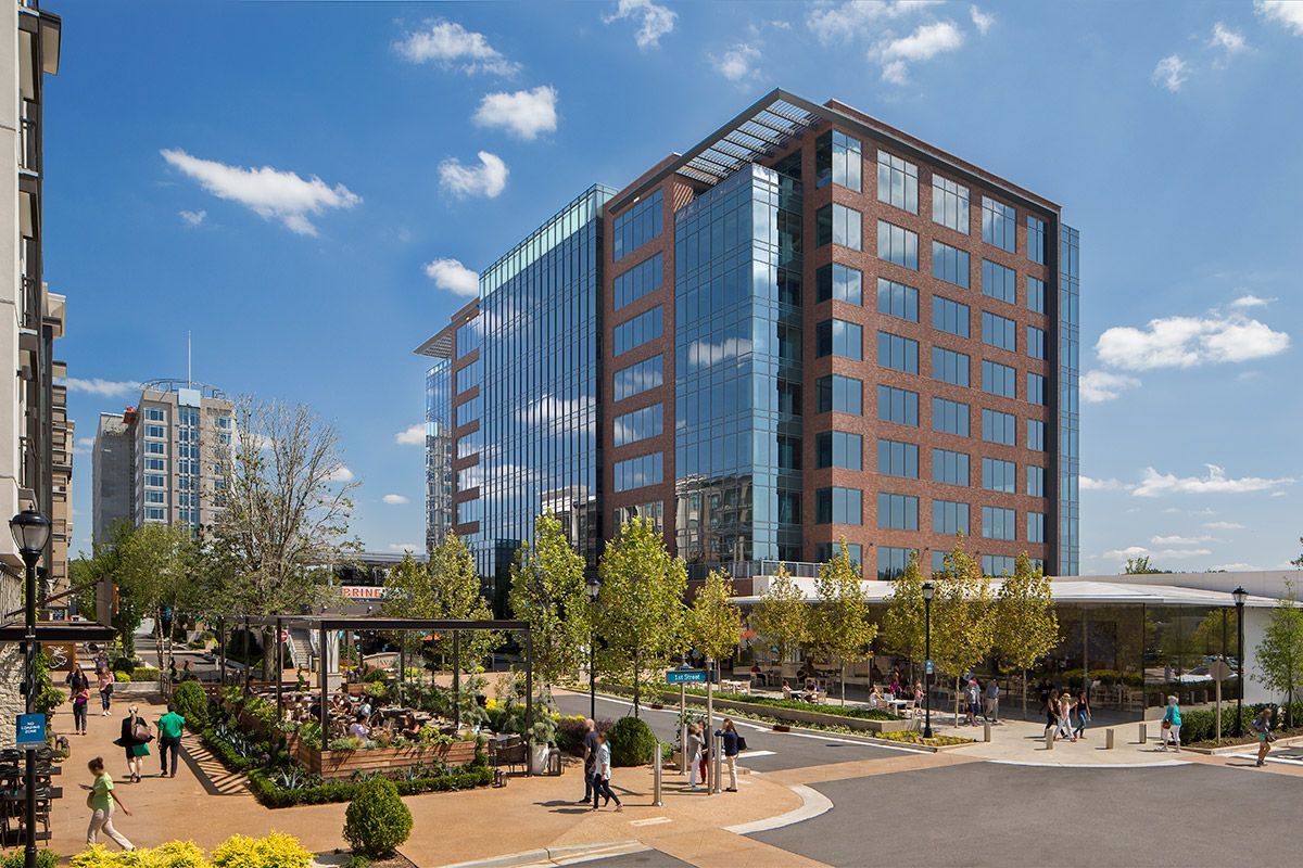Law office: wooden desk with laptop, papers, and statue of justice; wood-paneled walls and bookshelf.