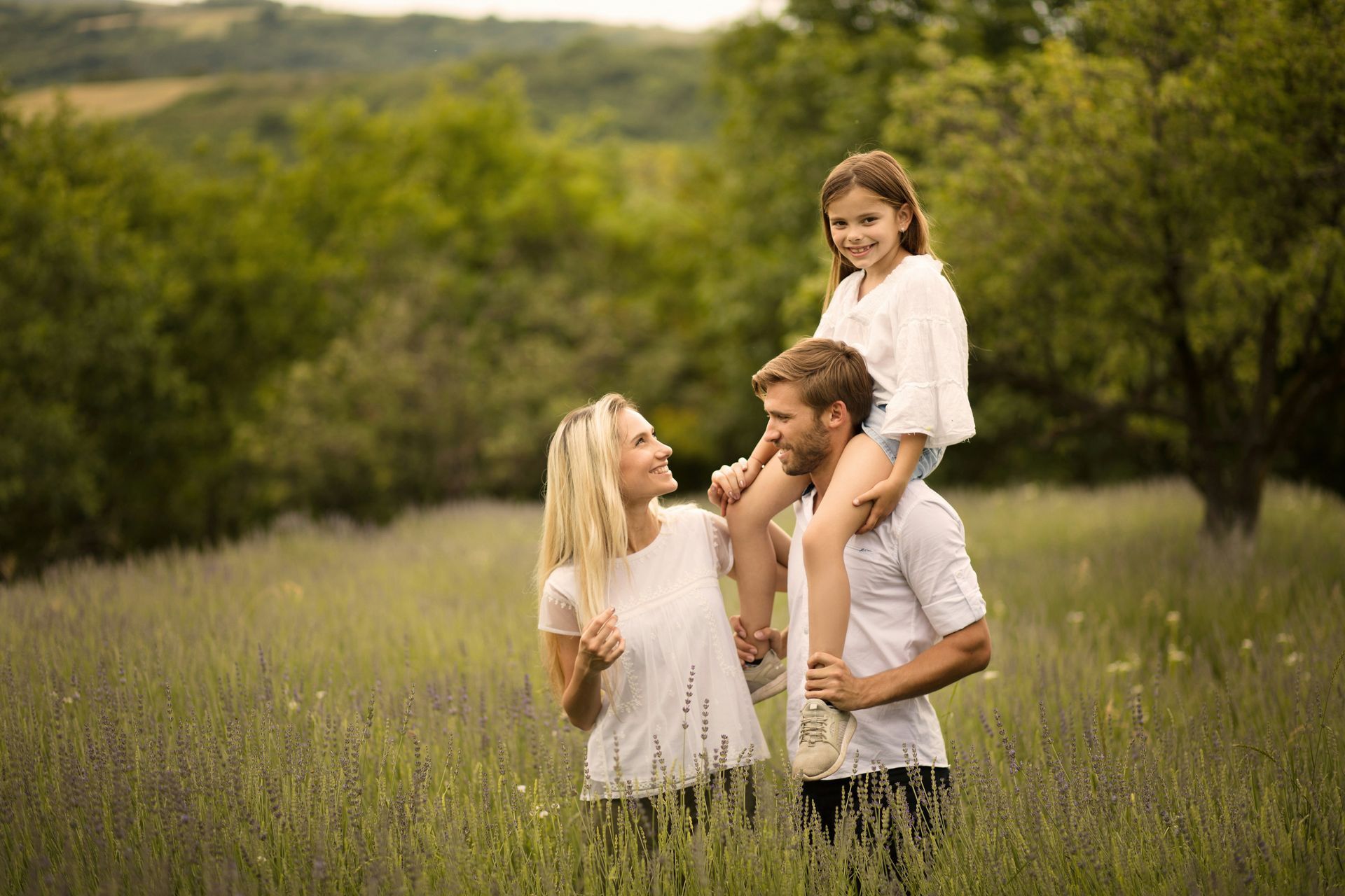 Woman curled up on a couch, covering her face. Man stands facing her, fist clenched. Interior setting.