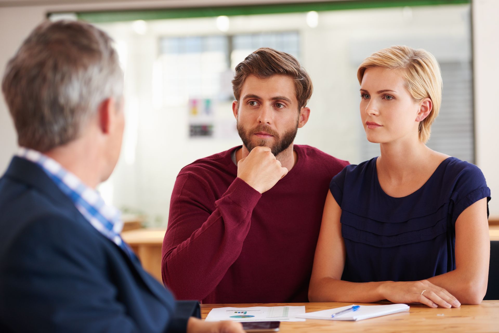 A financial advisor consults with a couple, sitting at a table.