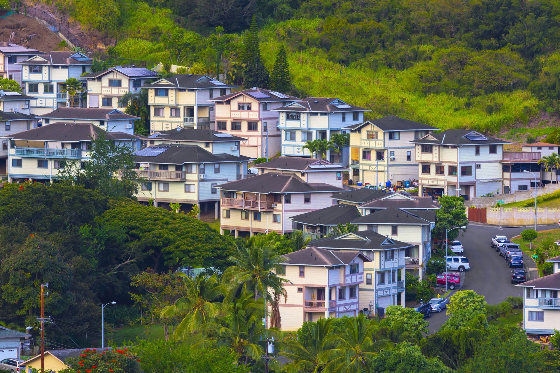A row of houses on a hillside surrounded by trees.