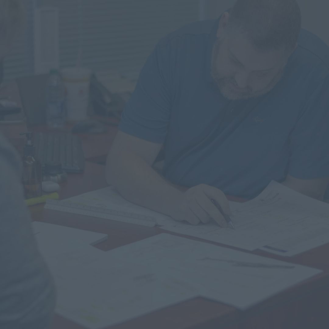 A man is sitting at a table writing on a piece of paper.