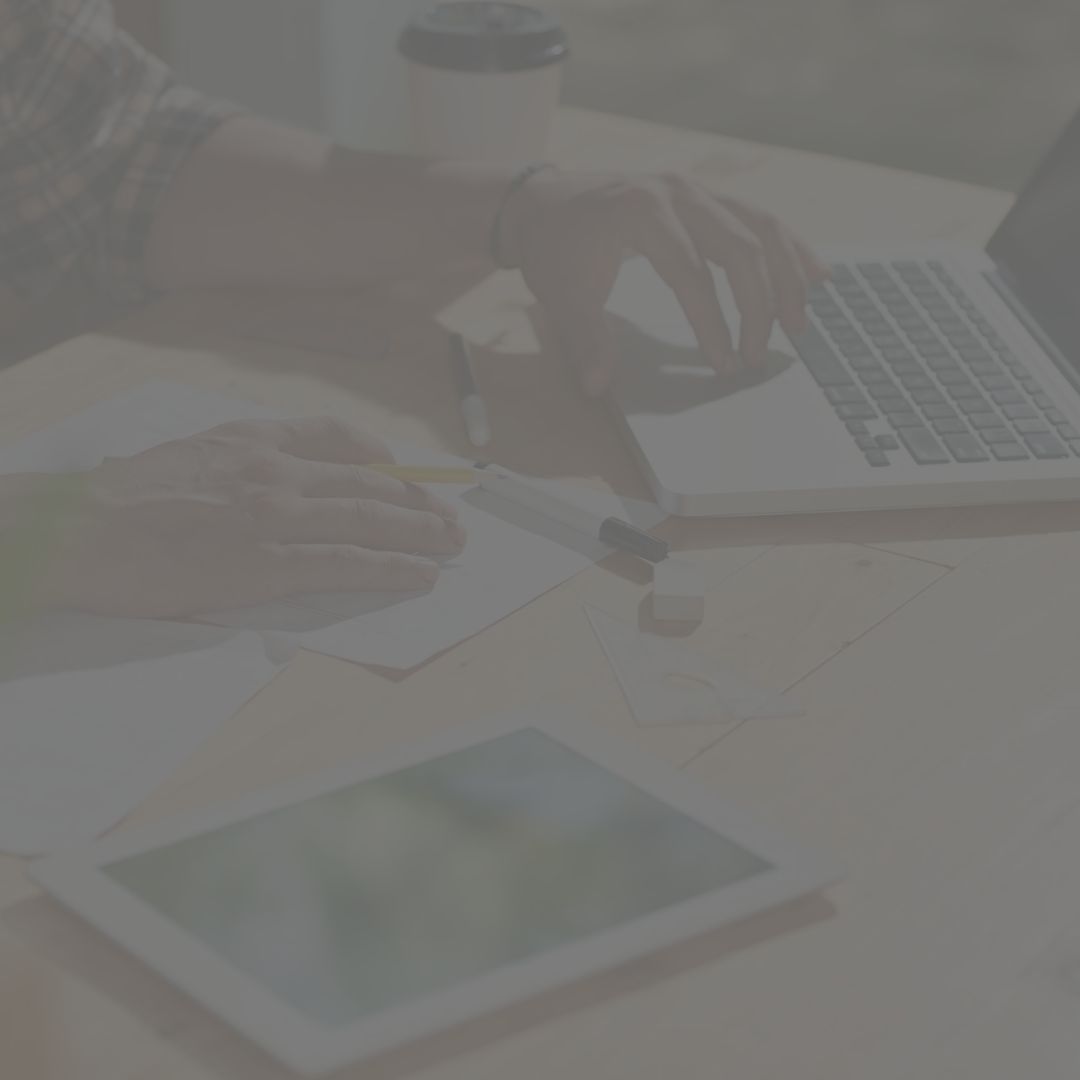 A person is sitting at a table using a laptop and a tablet.