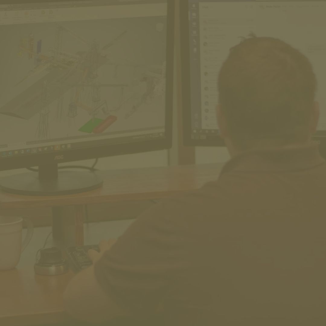 A man is sitting at a desk looking at a computer screen.