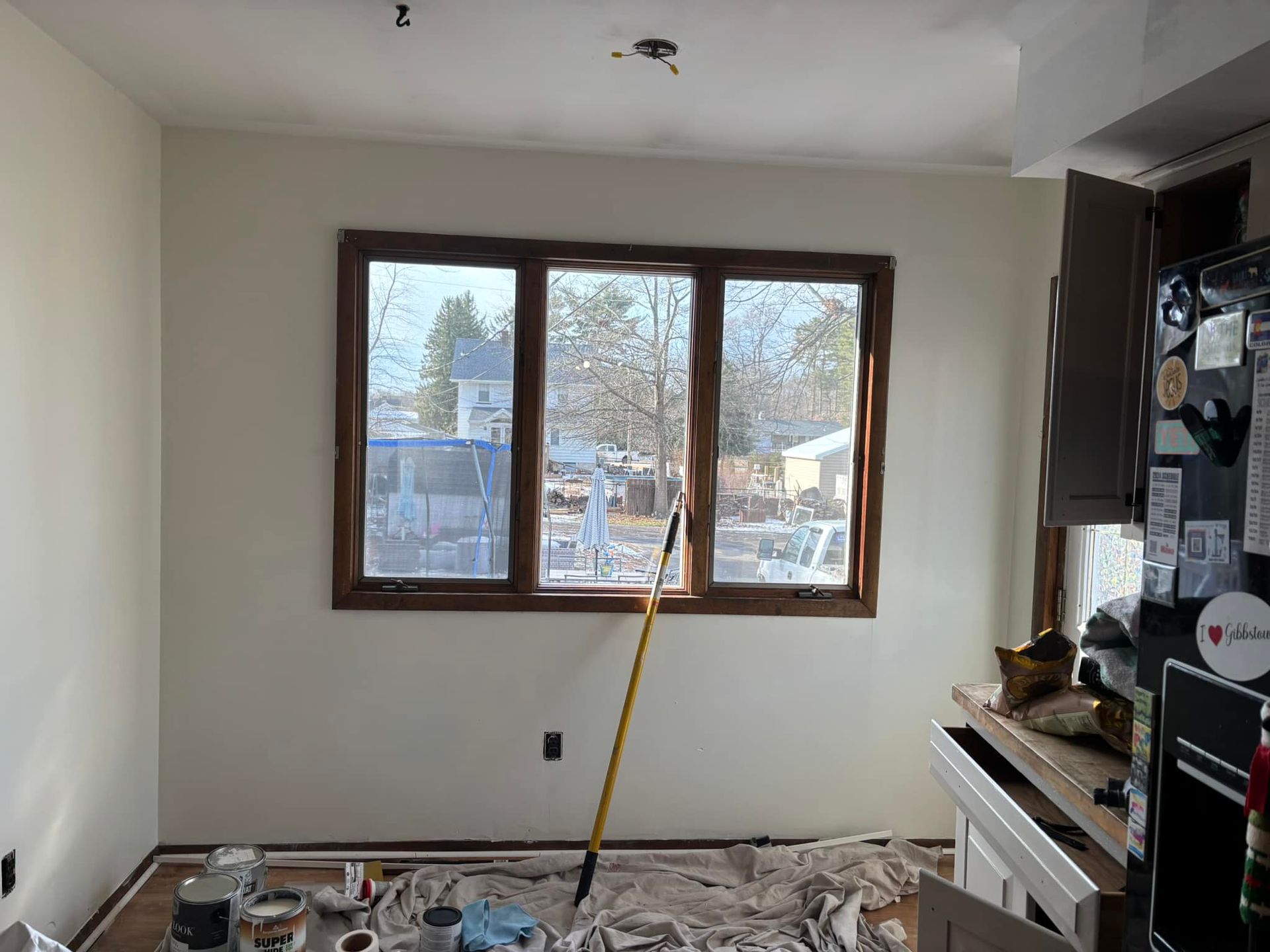A room with a window and a mop on the floor.