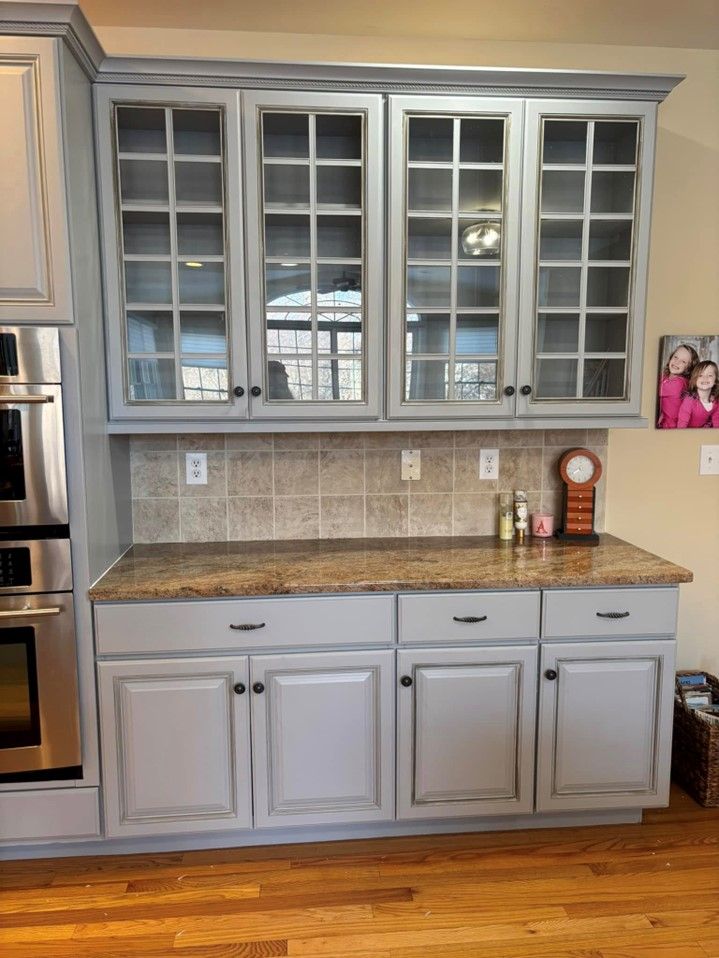 A kitchen with gray cabinets , granite counter tops , and stainless steel appliances.