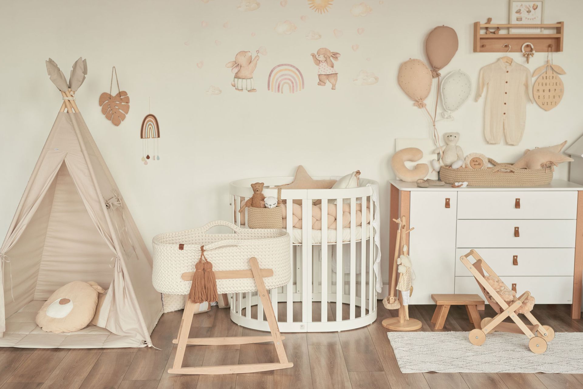 A baby room with a crib , dresser , teepee and rocking horse.