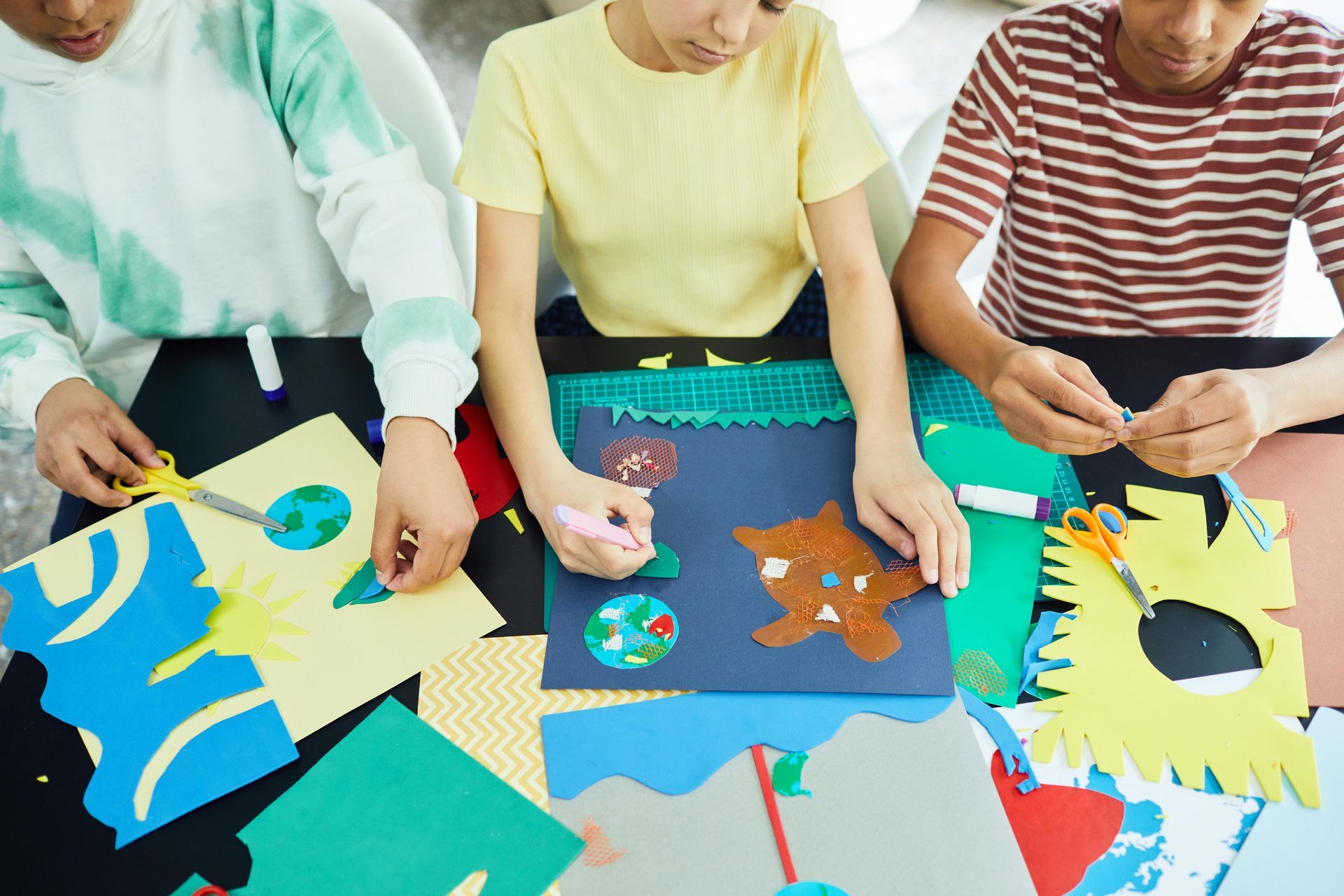 A group of children are sitting at a table making crafts at Kids Creation Stations in Tampa, FL.
