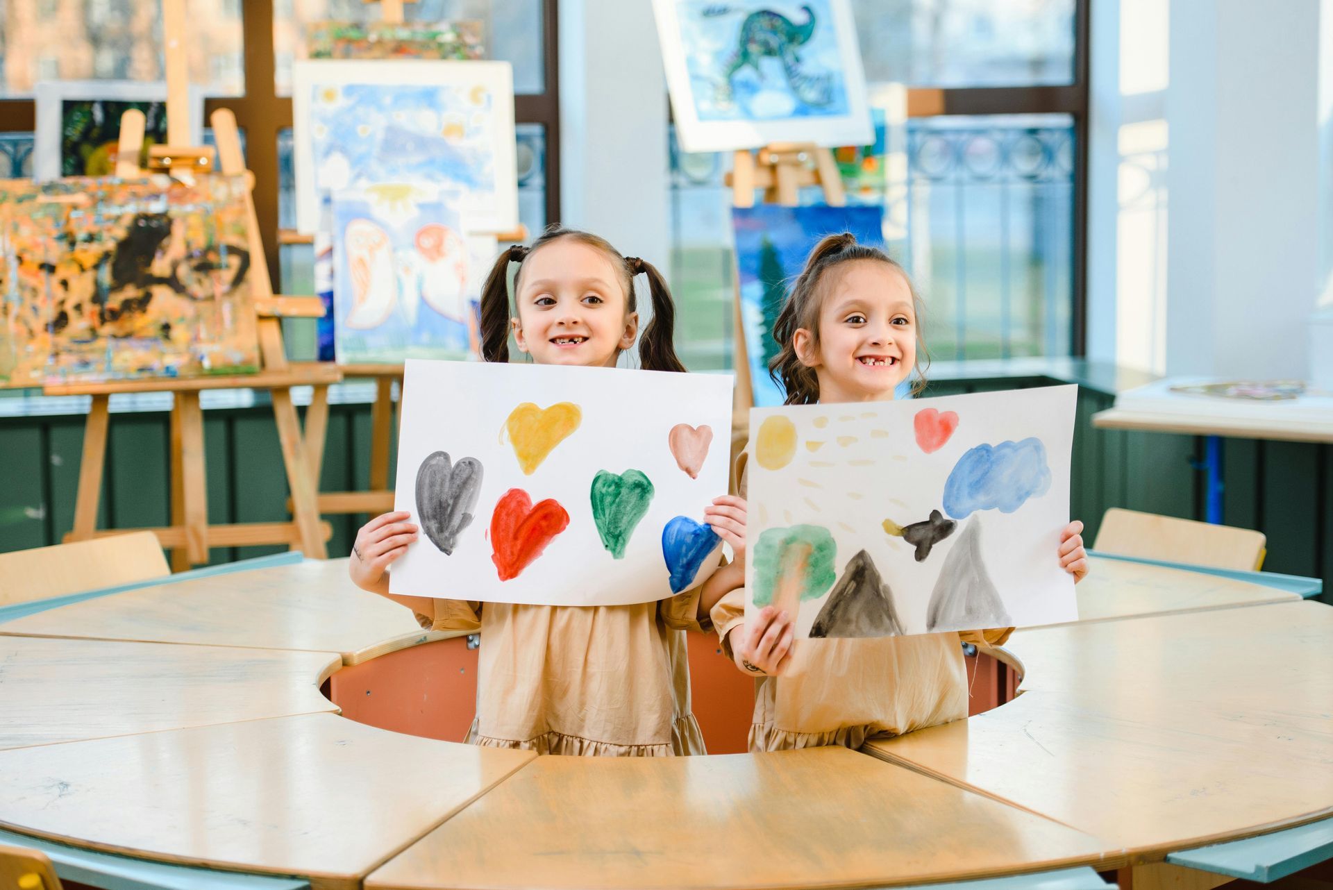 Two girls holding up art they made during an art class at Kids Creation Stations.