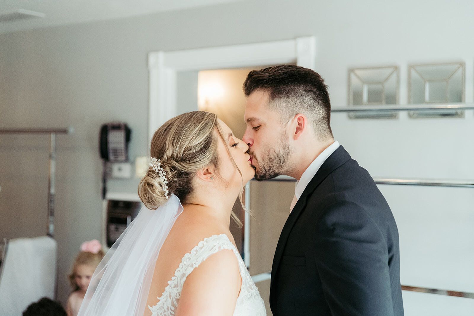Bride and groom kissing, indoors. Bride in dress and veil, groom in suit.