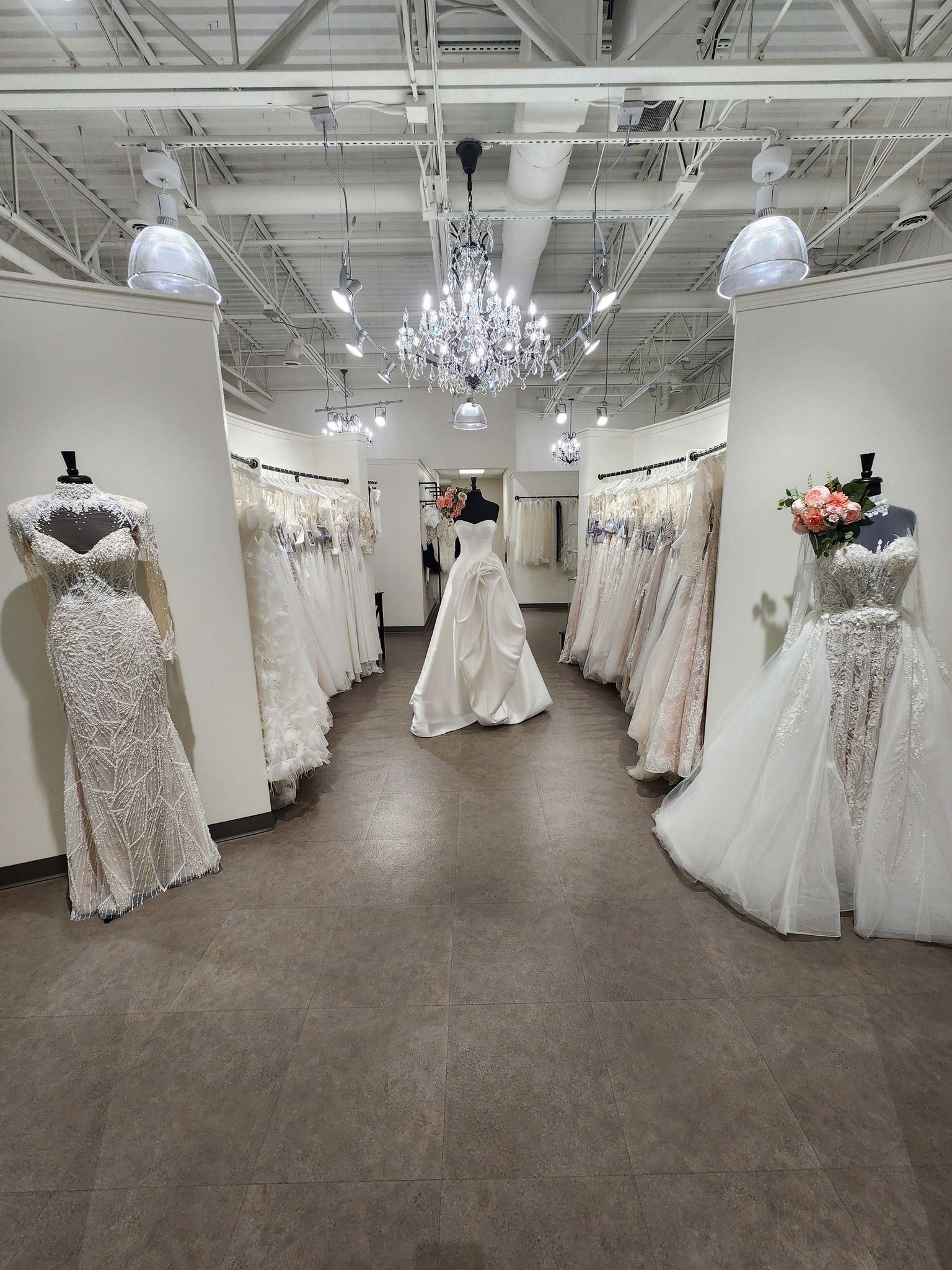 Wedding dresses hanging in a bridal shop, mostly out of focus.