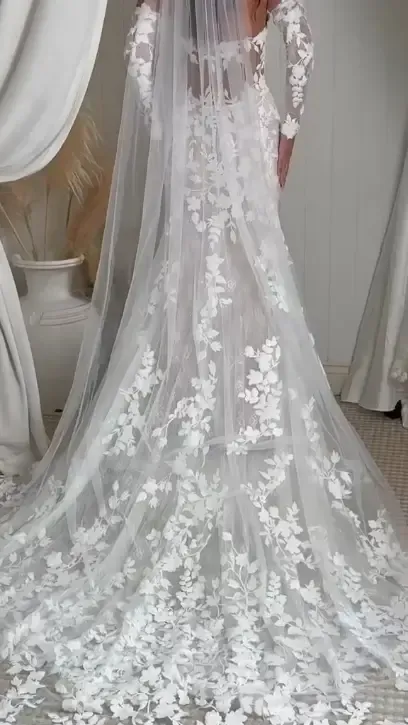 Woman in a flowing red gown stands on a cliff, arms outstretched, against a sunset backdrop.