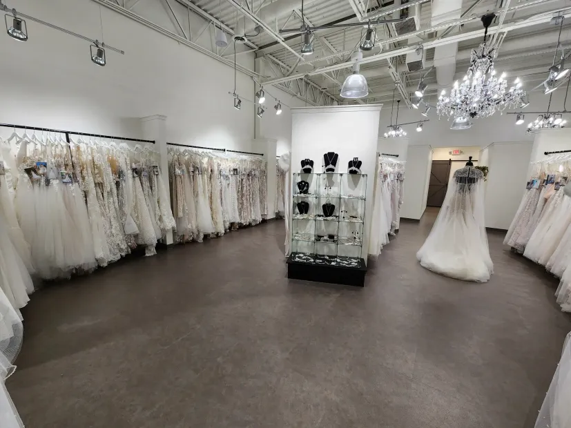 Inside a bridal shop, a black gown on a mannequin stands out amid rows of white dresses.