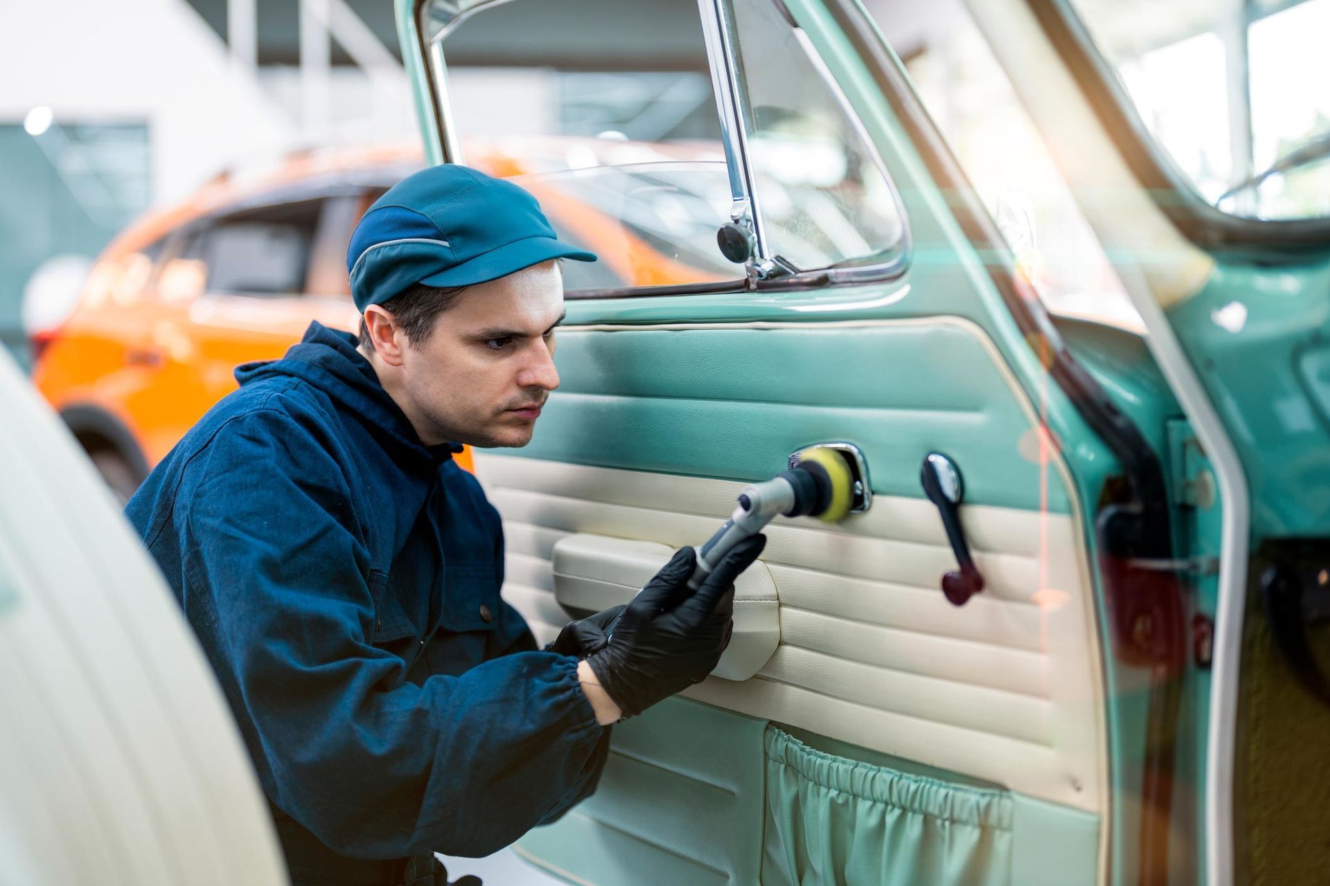 Professional technician performing auto interior detailing in Hanover, VA by cleaning and polishing a car door panel with specialized equipment.