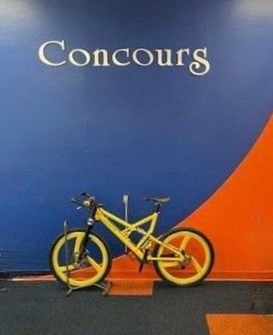Yellow mountain bike in front of a blue and orange wall with 