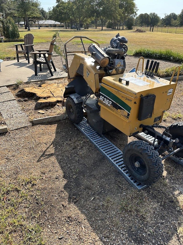 A stump grinder is sitting on the ground in a park.