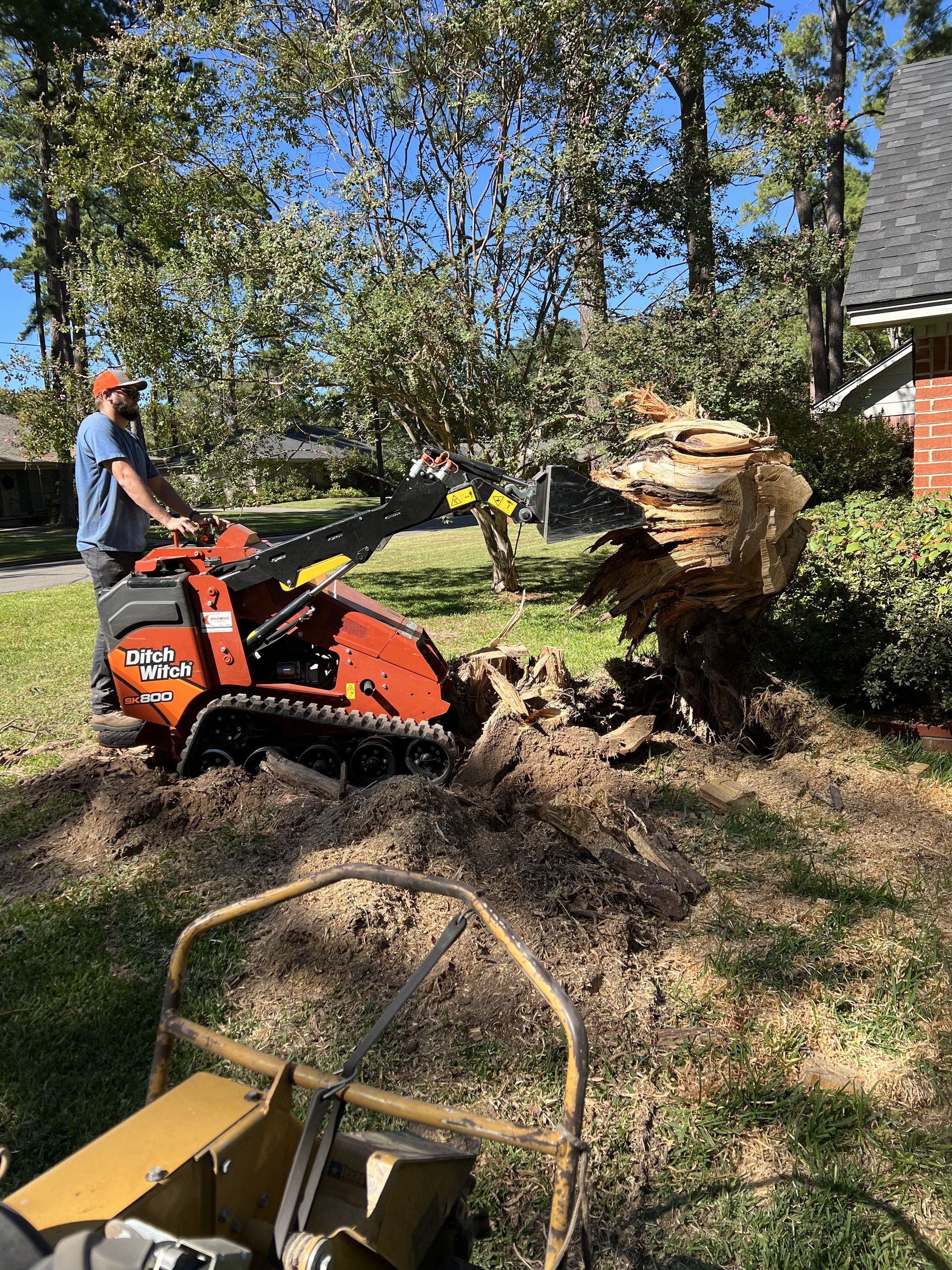 A man is using a stump grinder to remove a tree stump.