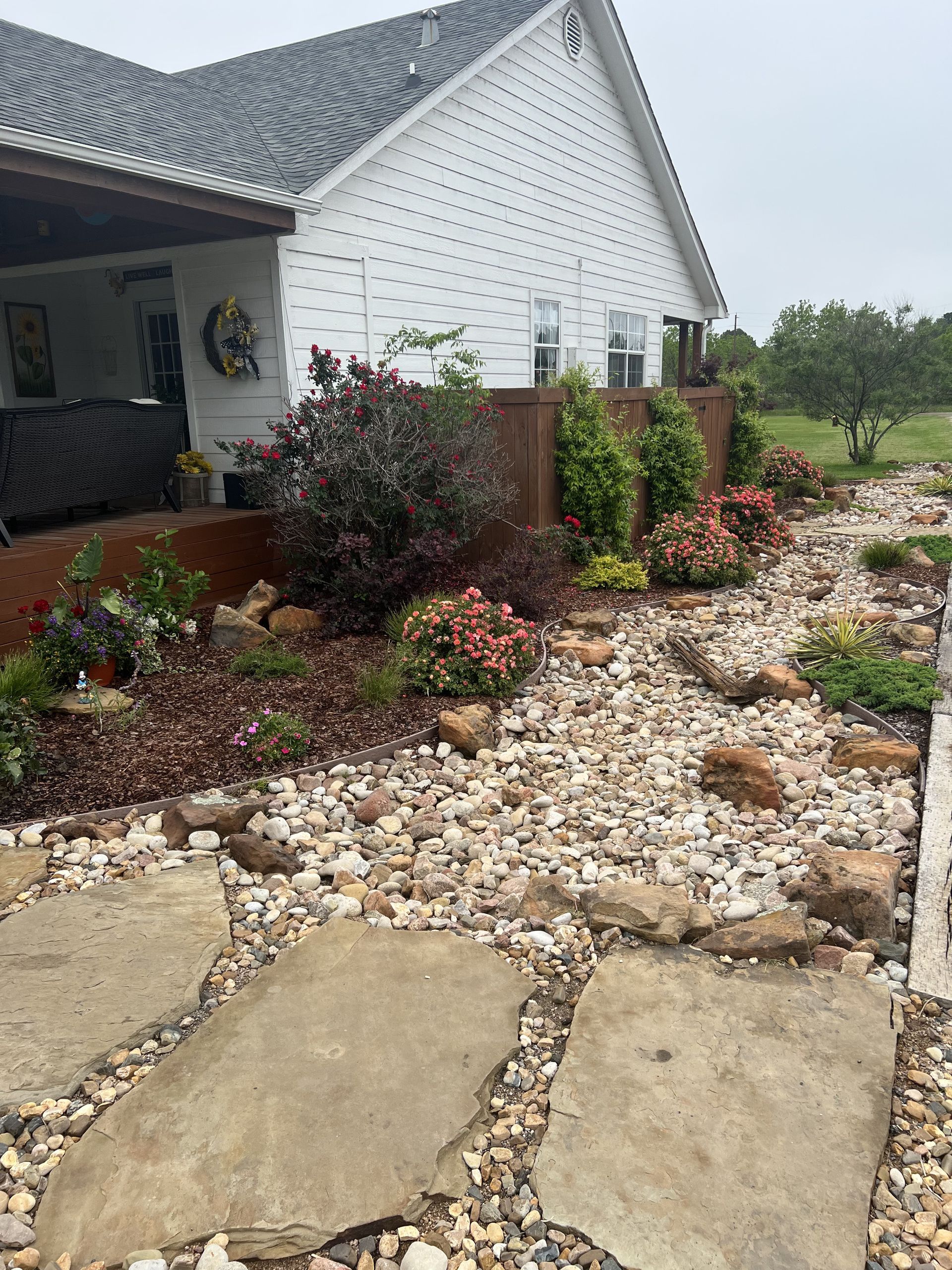A white house with a rock garden in front of it.