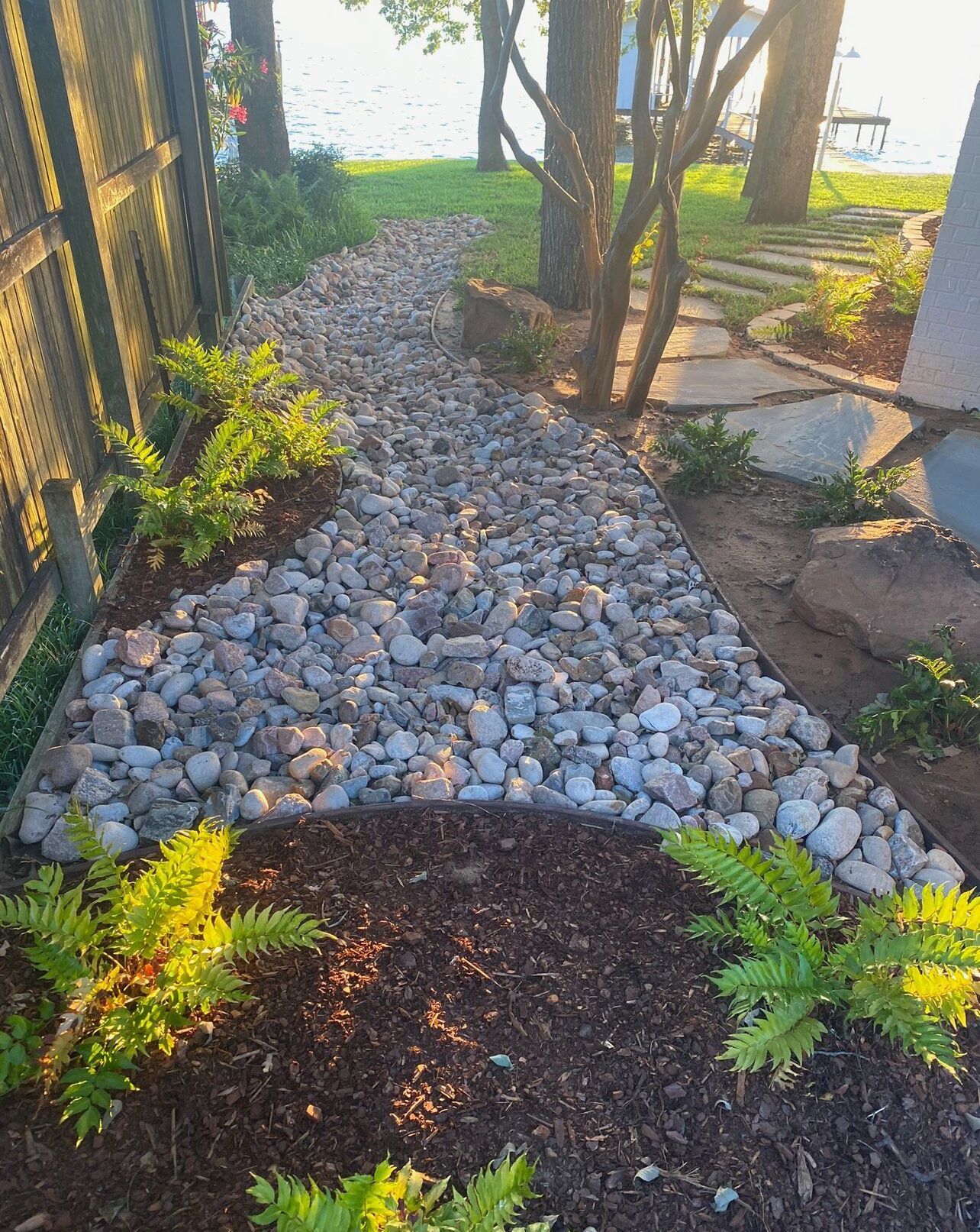 A path surrounded by rocks and plants leading to a body of water.