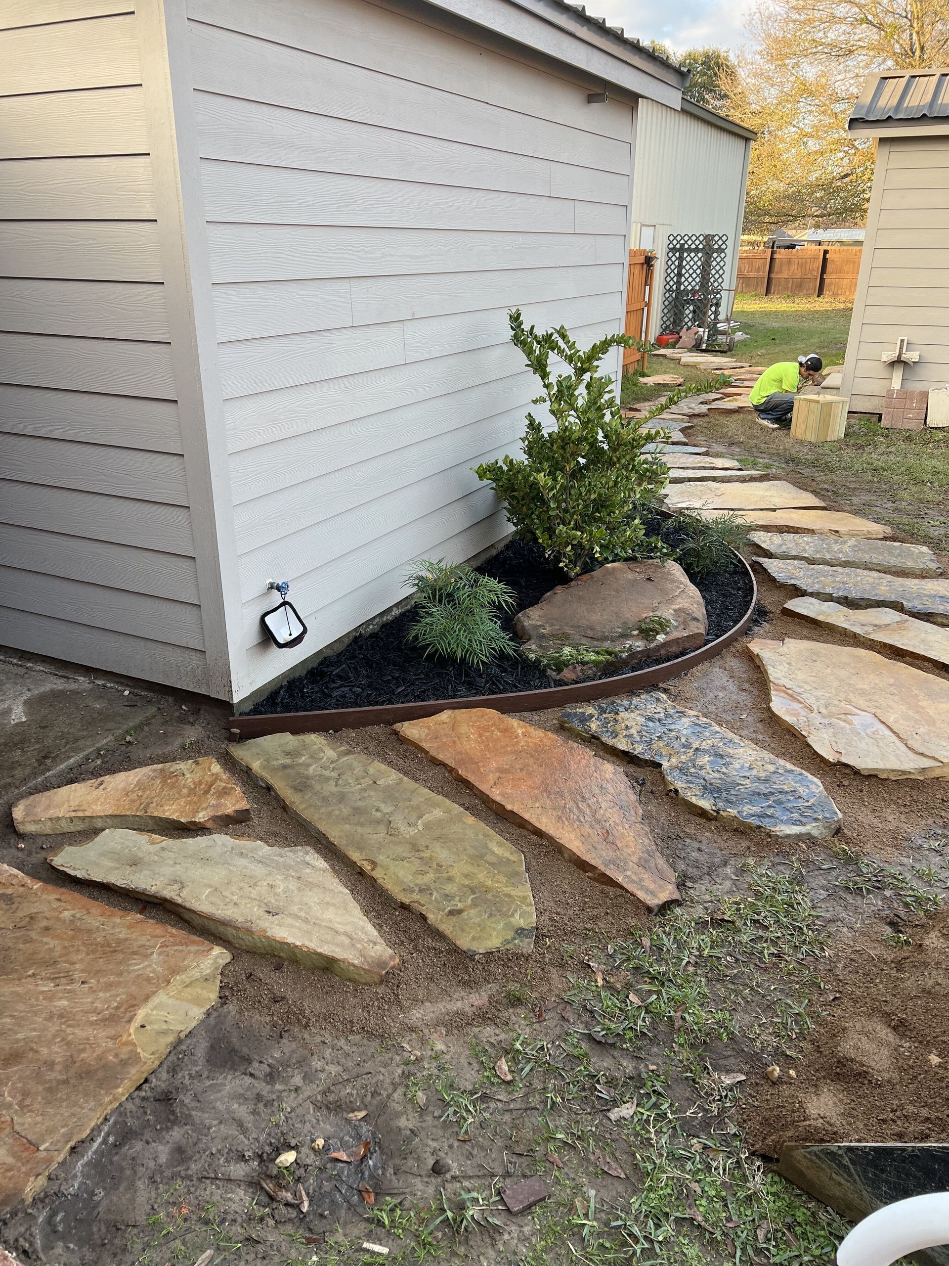 A stone walkway is being built in front of a house.