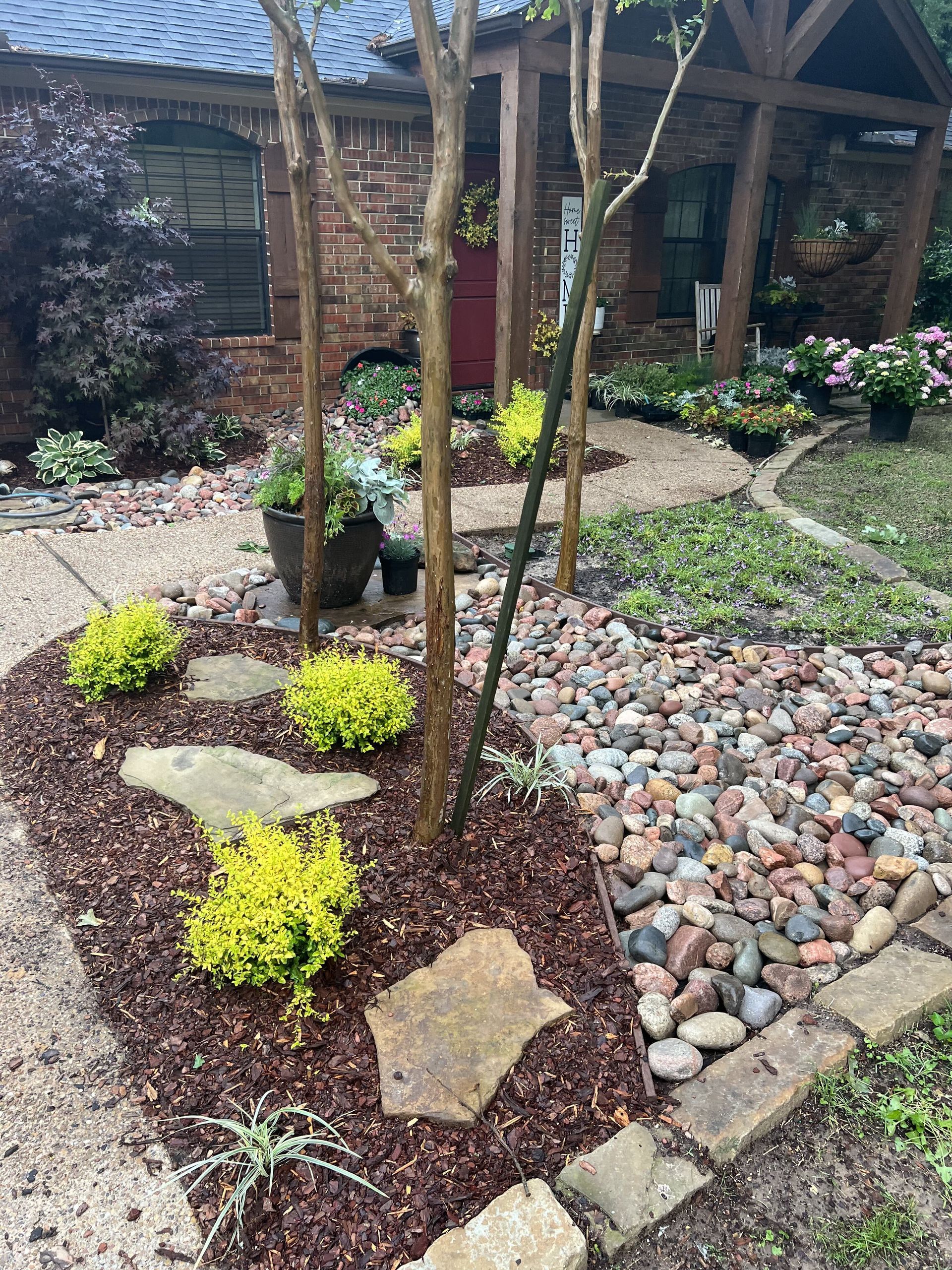 A garden with rocks and plants in front of a brick house.