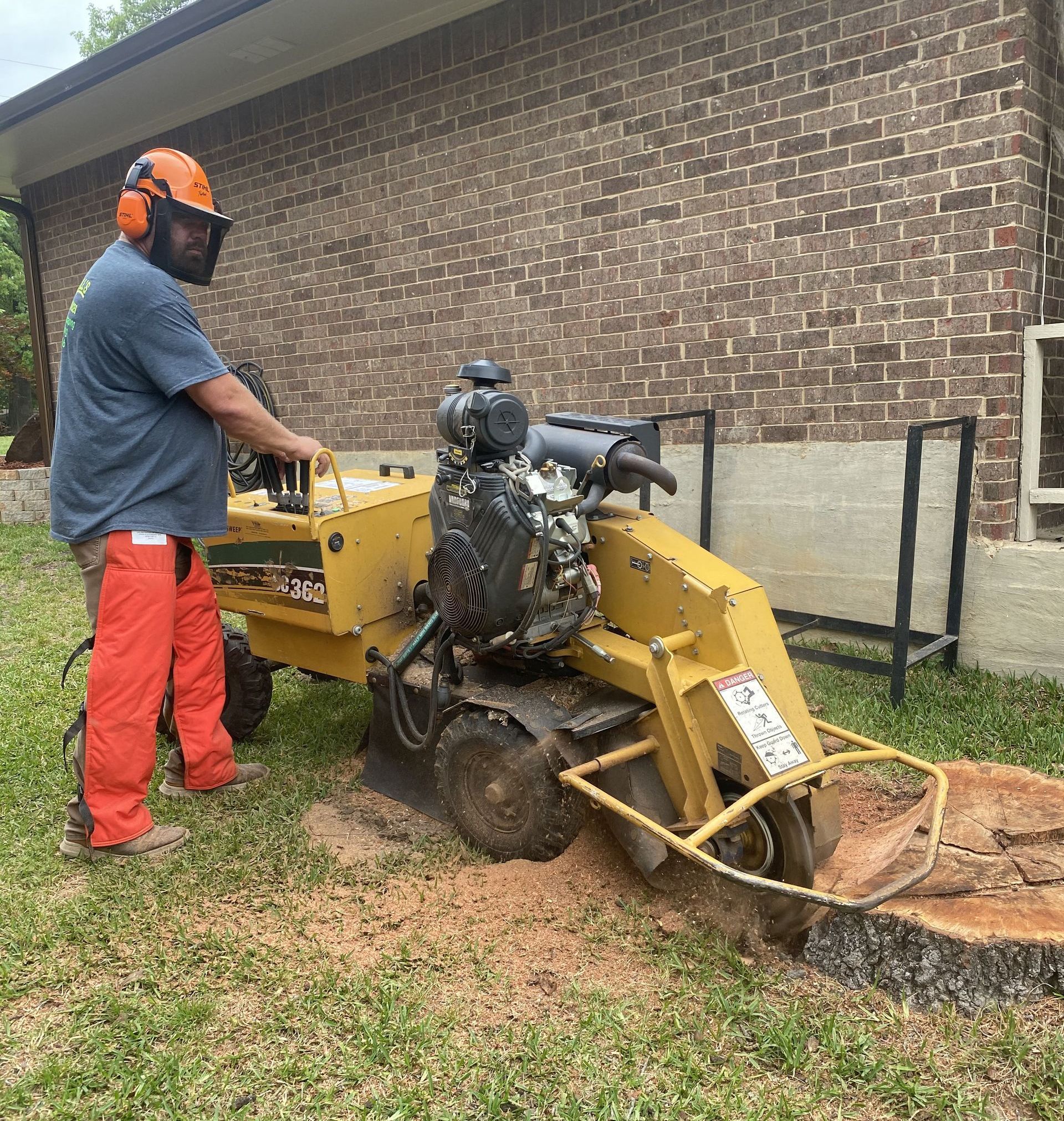 A man is using a stump grinder to remove a tree stump.