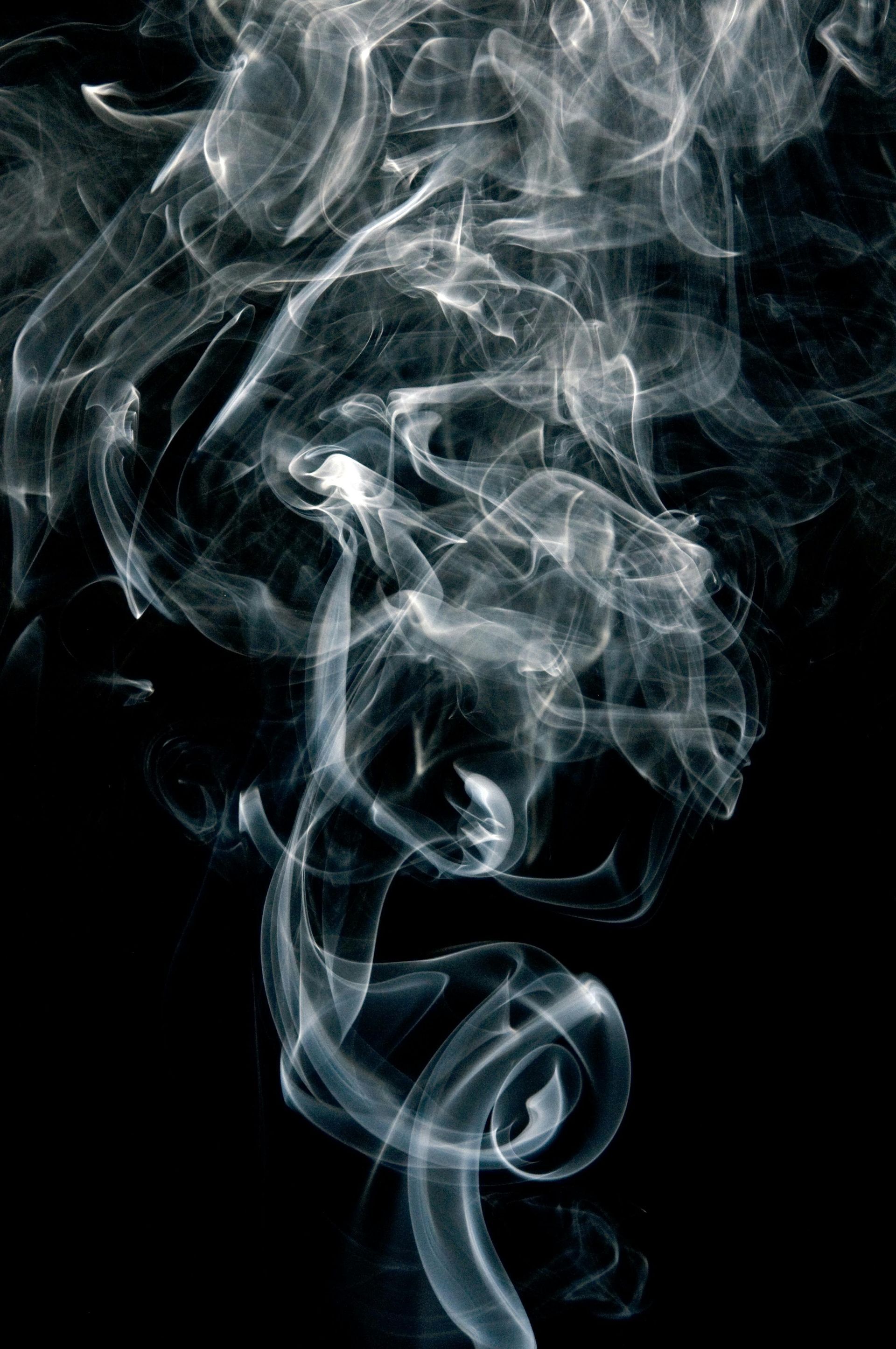 Wispy white smoke against a black background, swirling upwards.