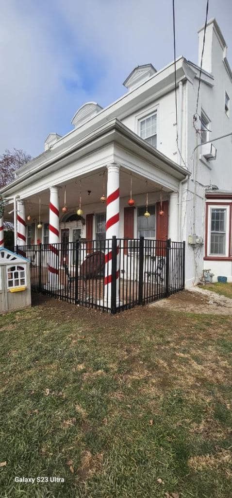 White building with a porch decorated with red and white candy cane stripes. A black fence surrounds the porch.