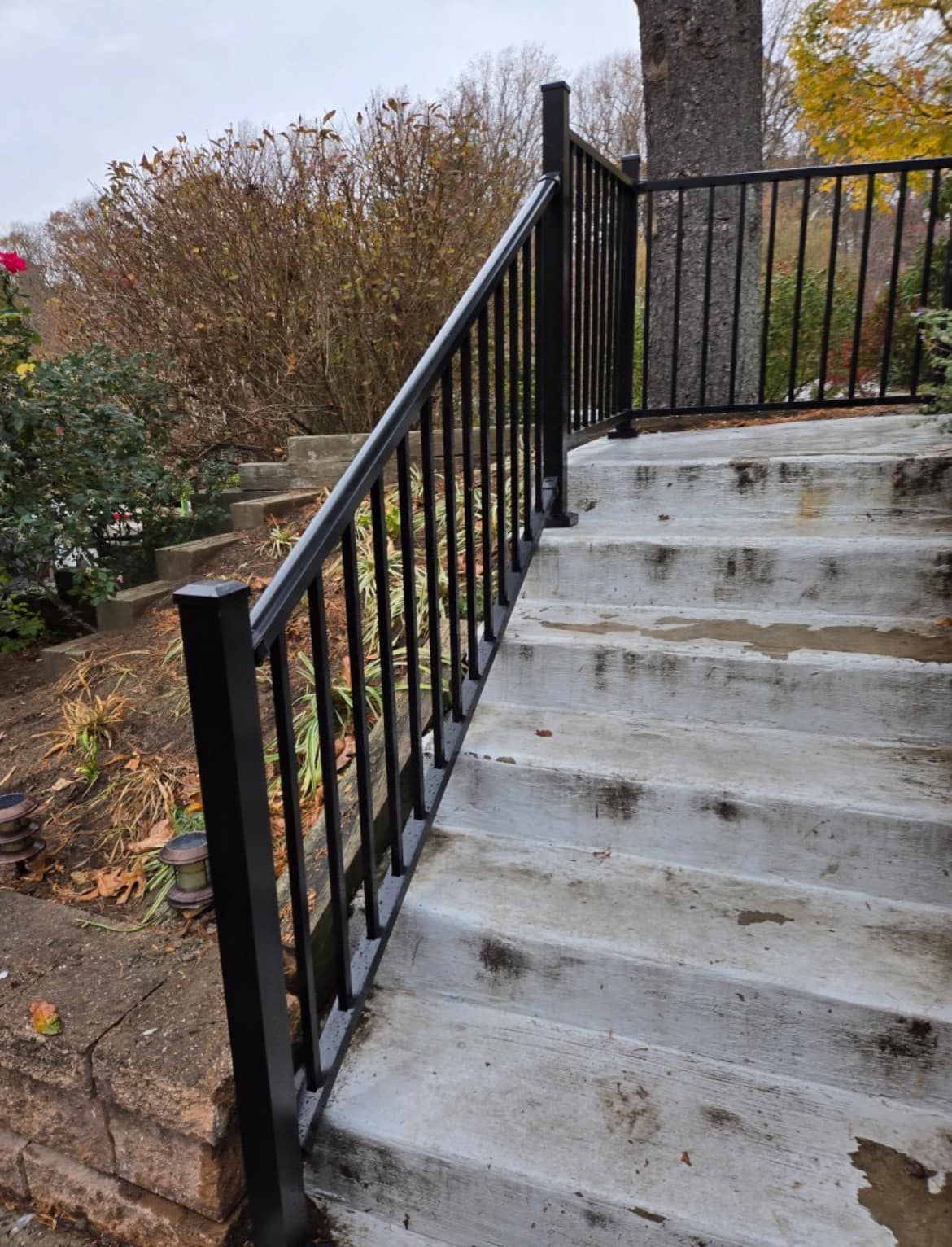 Black metal railing along outdoor concrete stairs.