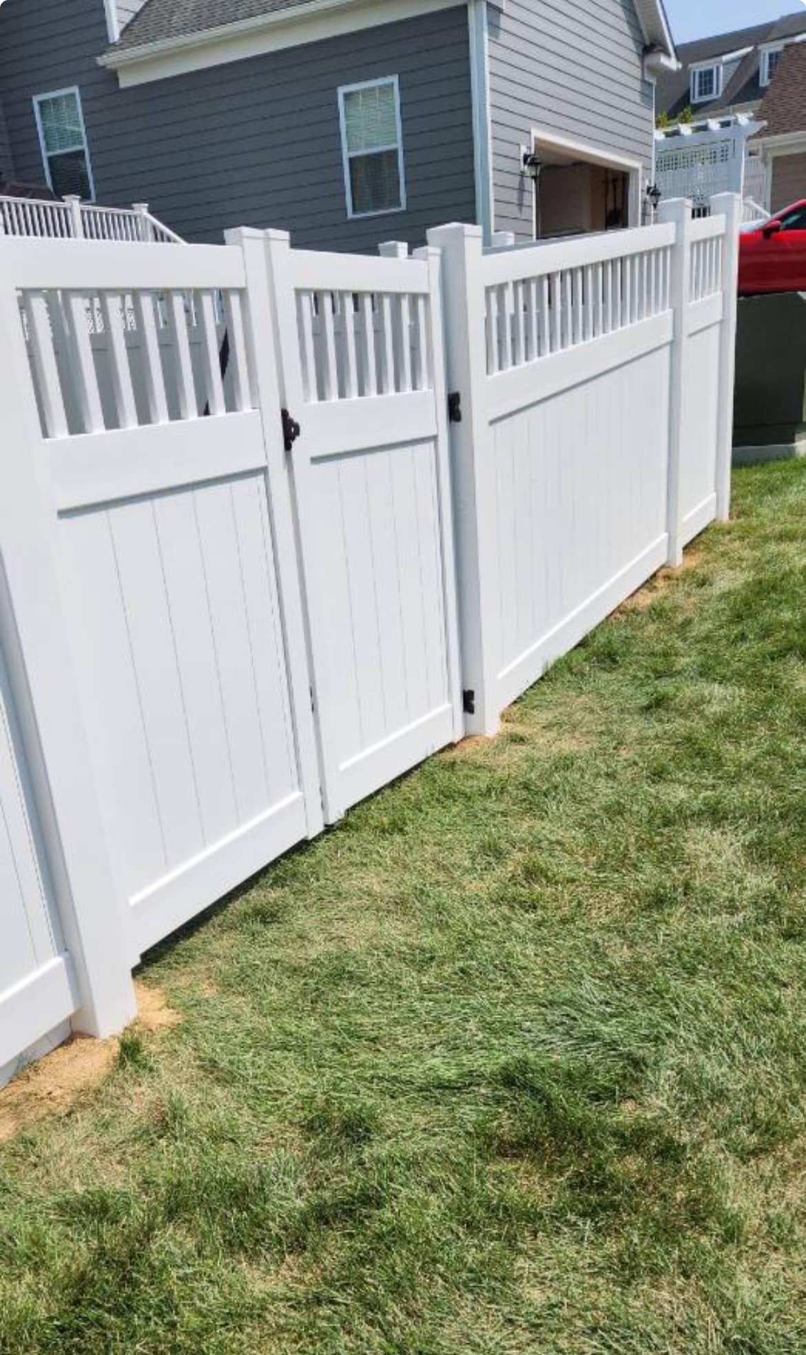 White vinyl fence with gate in a grassy yard.