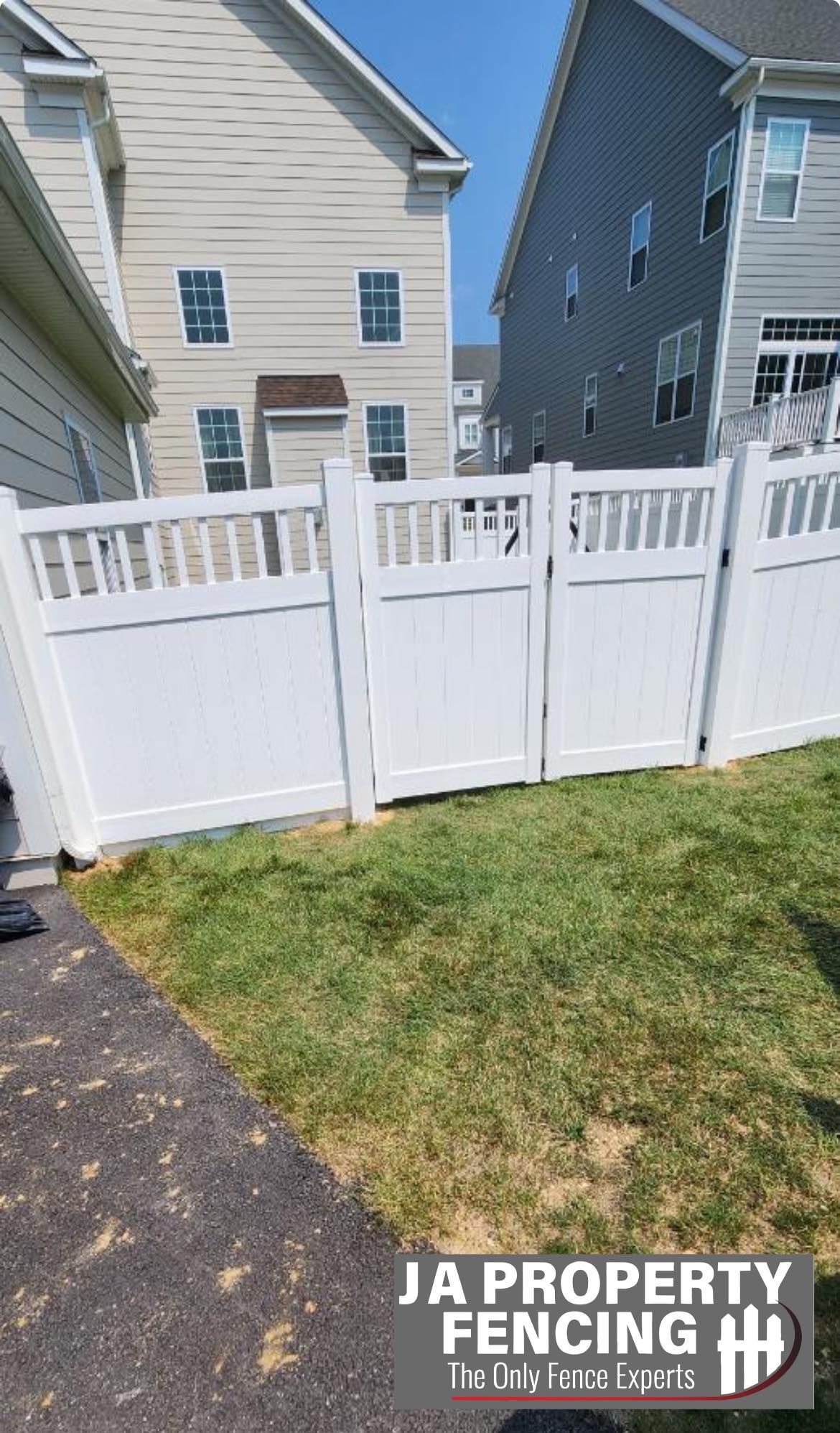 White vinyl fence in front of two-story houses. JA Property Fencing logo visible.