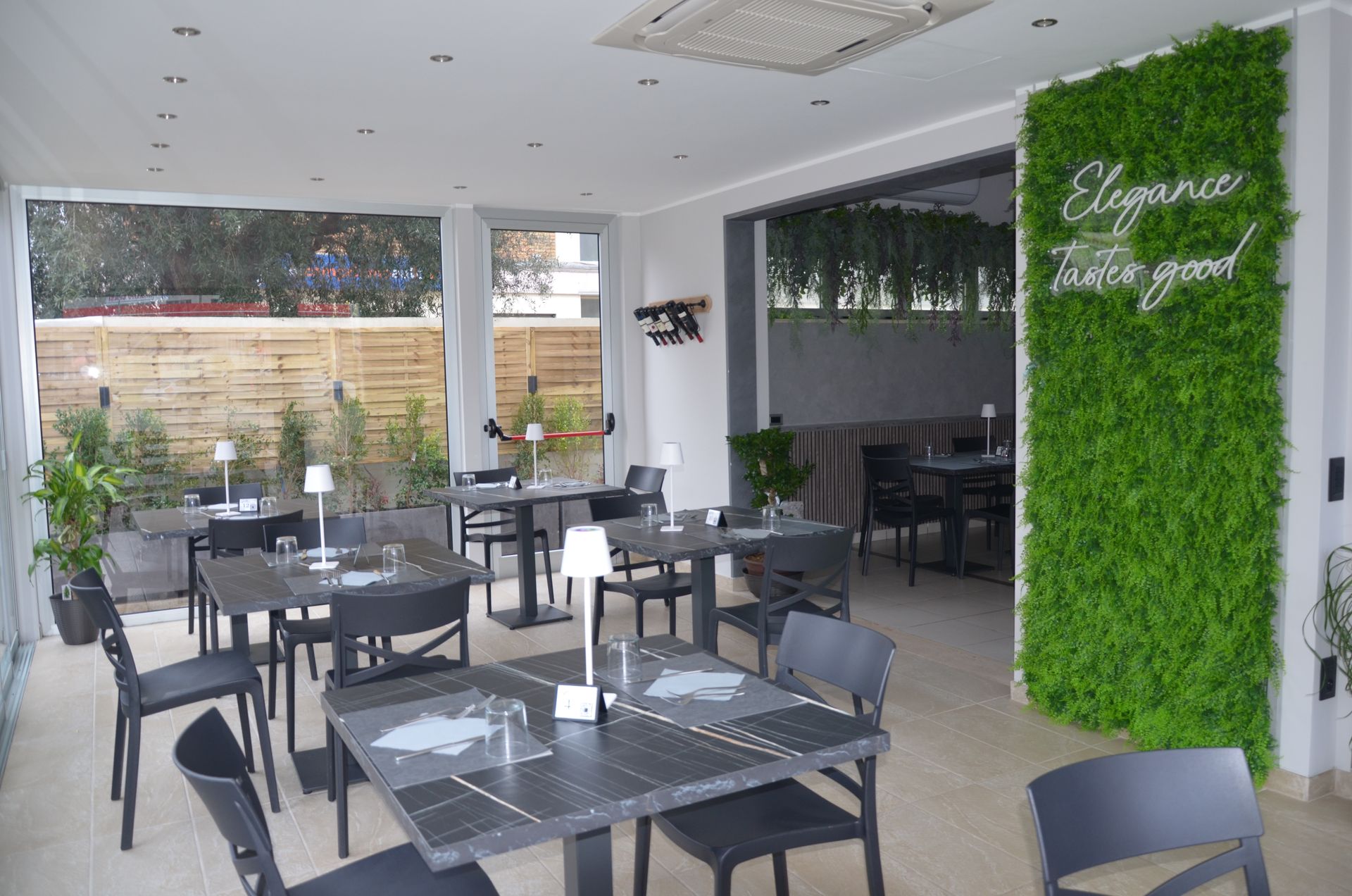 Interno di un ristorante con tavoli e sedie. Parete verde con la scritta 