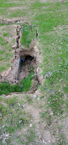 There is a hole in the ground in the grass.