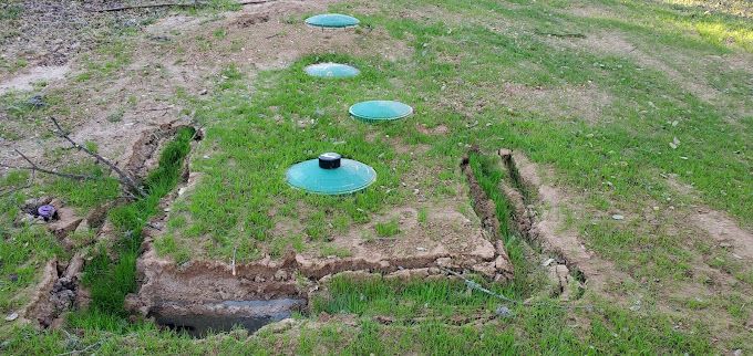 A row of septic tanks sitting on top of a lush green field.