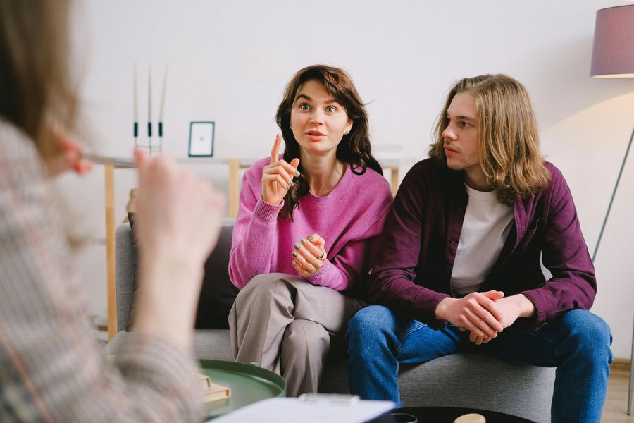 A man and a woman are sitting on a couch talking to a woman.