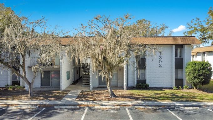 A white apartment building with a parking lot in front of it.