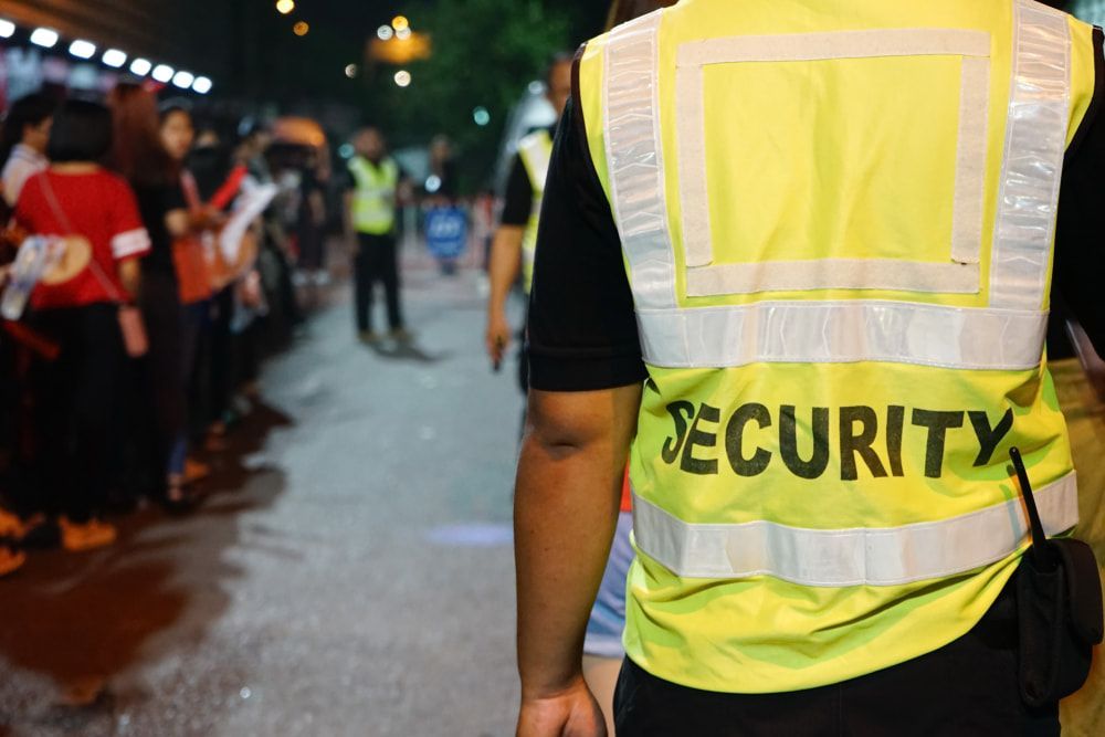 A Security Personnel Wearing a Yellow Vest Standing in Front of The Entrance Line — Cleaning & Security in Ingham QLD