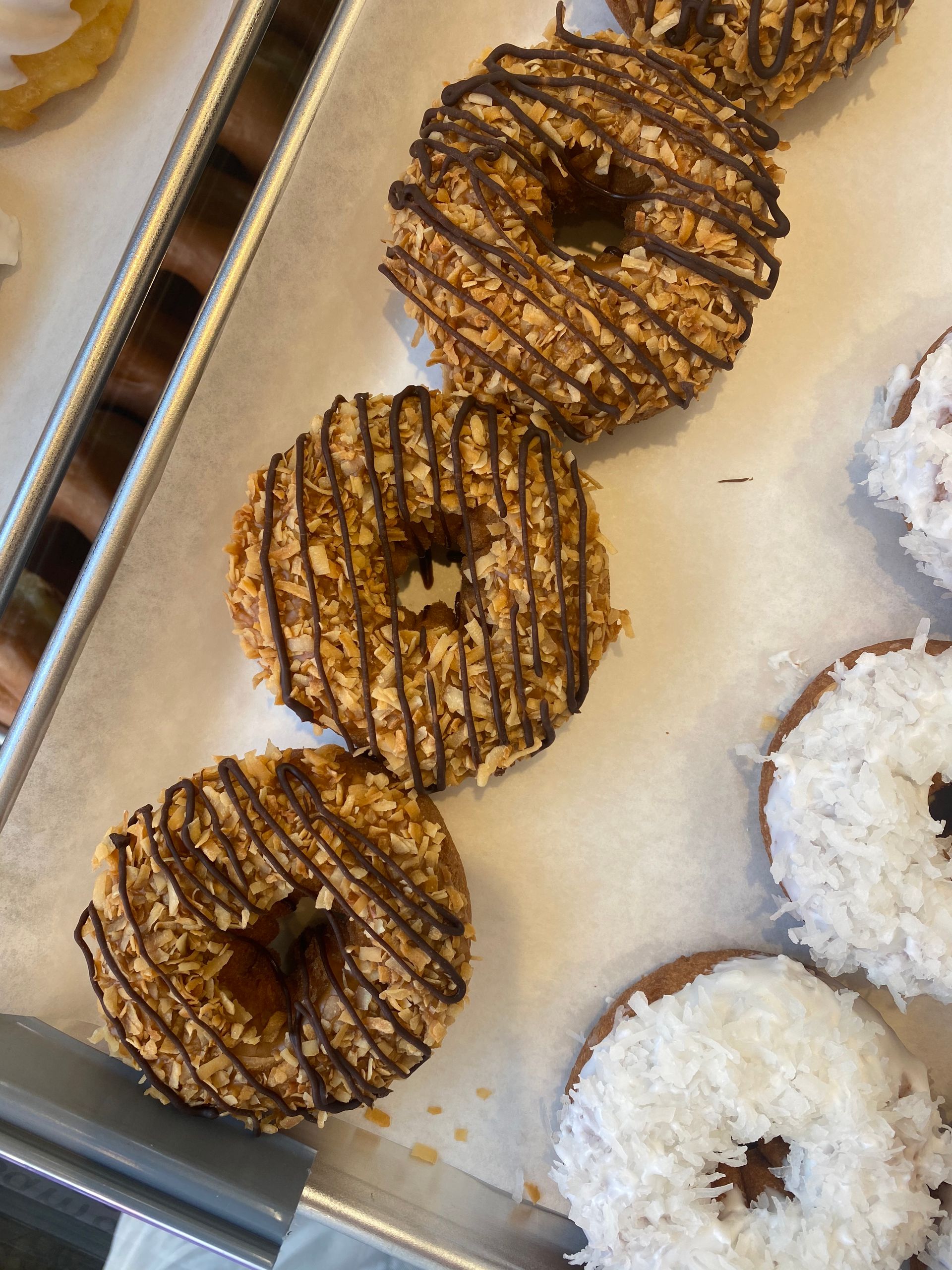 A tray of donuts with chocolate and coconut on them