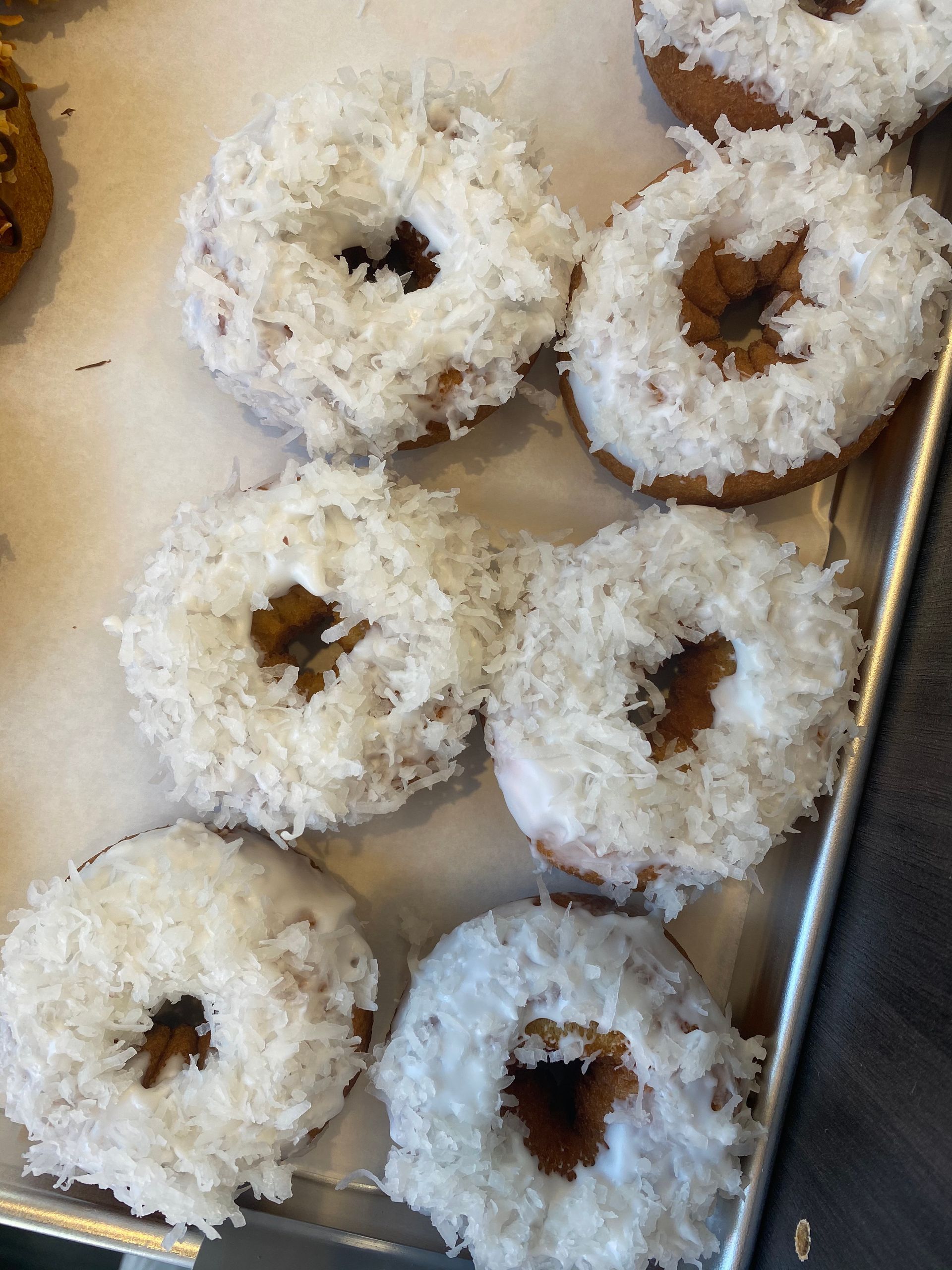 A tray of donuts with white frosting and coconut on them