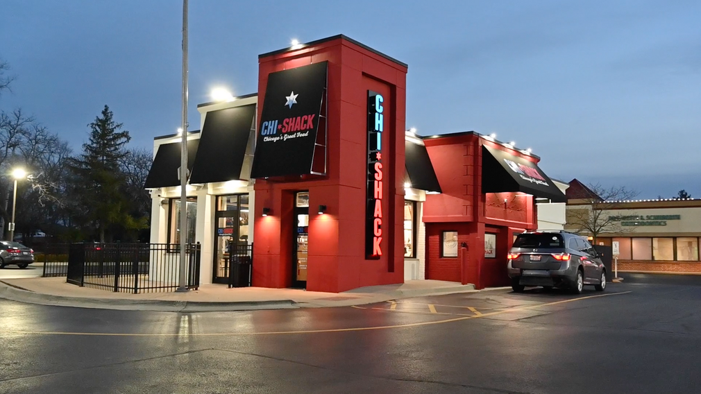 A car is parked in front of a red and white building.