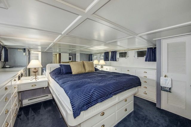 Bedroom on a yacht with a large bed, white furniture, blue accents, and multiple drawers.