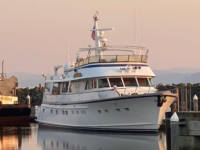 White yacht docked at a pier; the sky is pink at sunset.